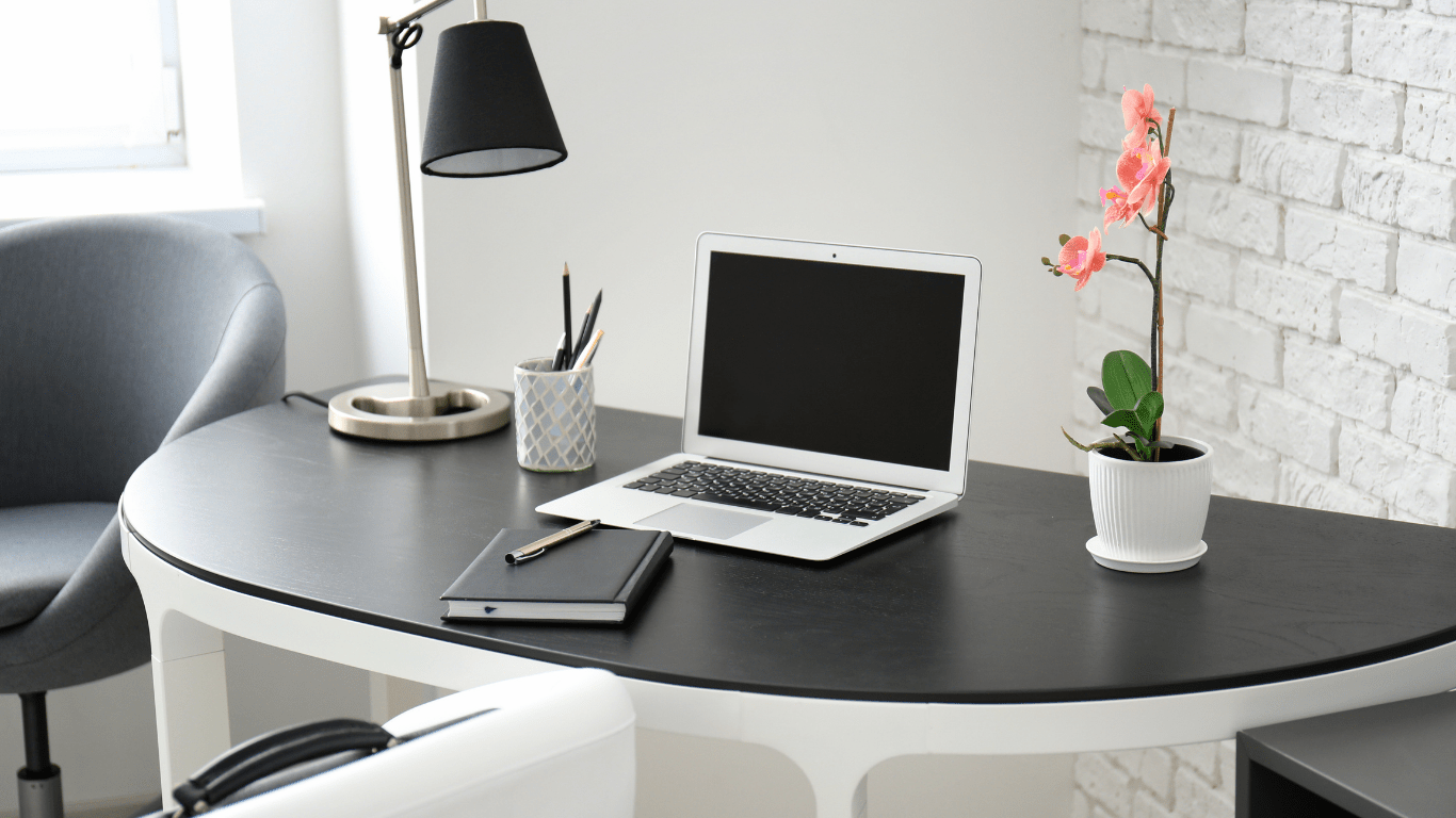 black desk with laptop lamp flower and day planner