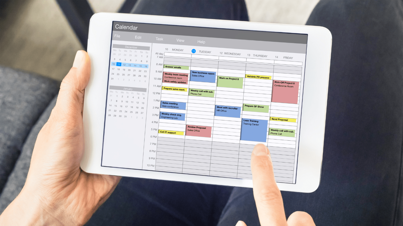 person holding white ipad with calendar displayed