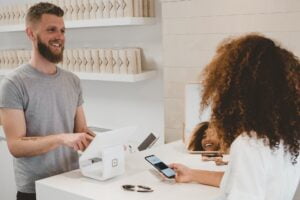 man behind check out accepting payment from woman