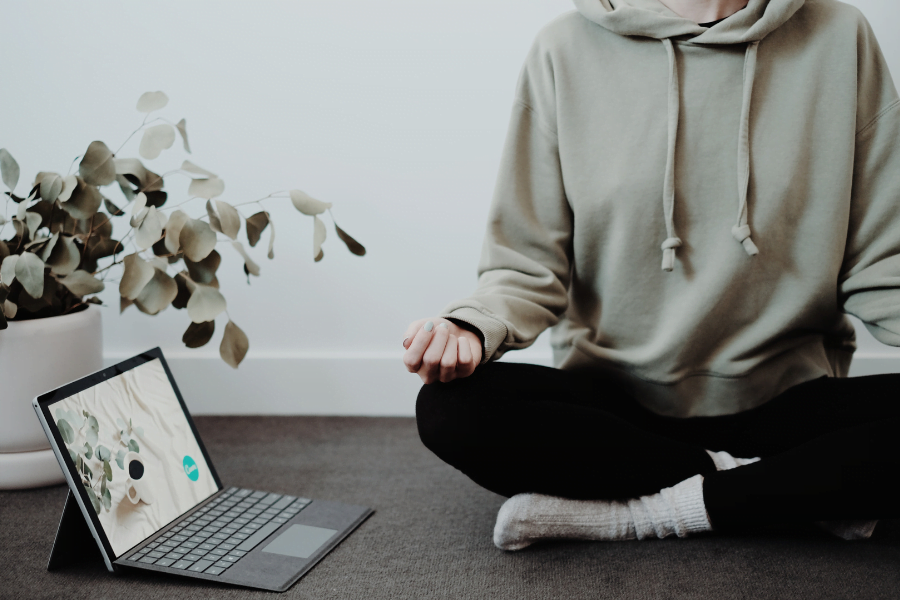 person meditating beside a laptop