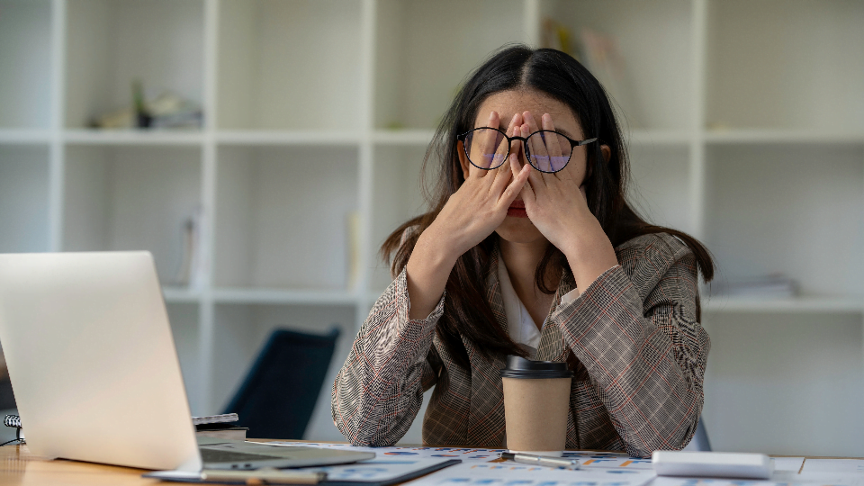 How Toxic Productivity Can Derail Your Best Laid Plans as a Small Business Owner 2 woman sitting at a desk with laptop and covering her eyes