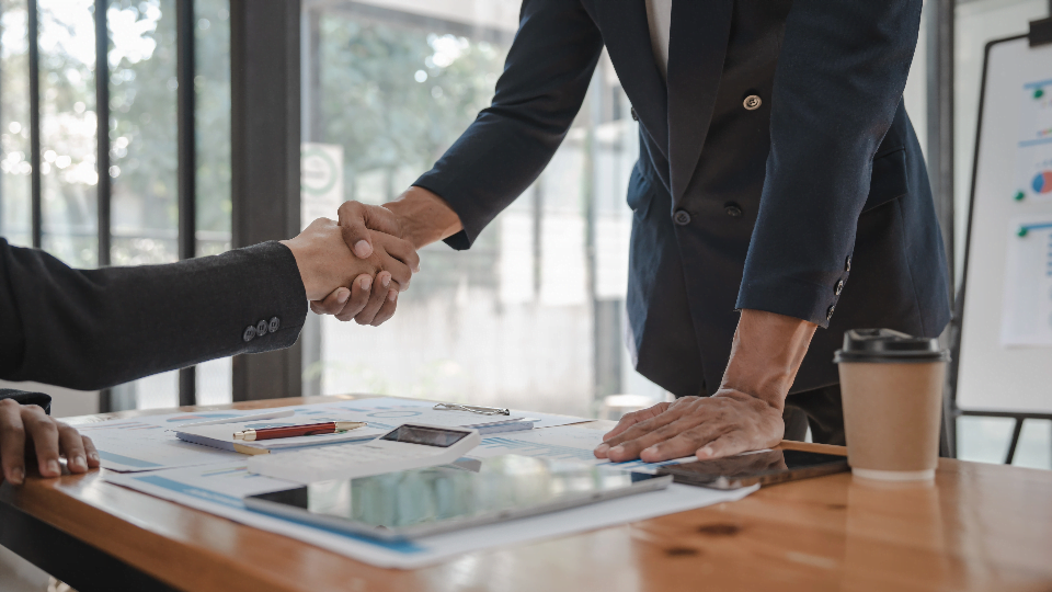 two people shaking hands over a desk