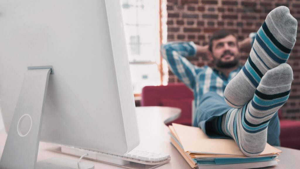 man with hands behind his head and feet up on desk