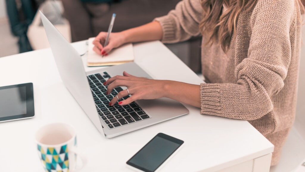 woman working on laptop and making notes
