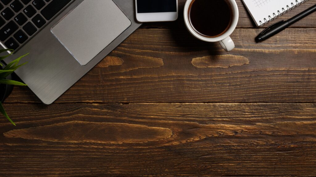 wood desk with a cup of coffee and a laptop